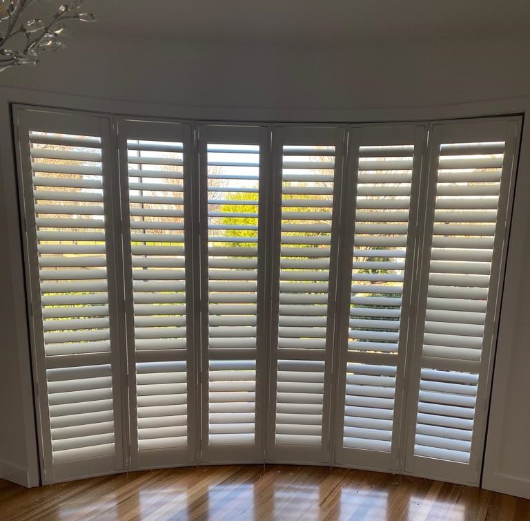 Plantation shutters installed on a Curved bay window