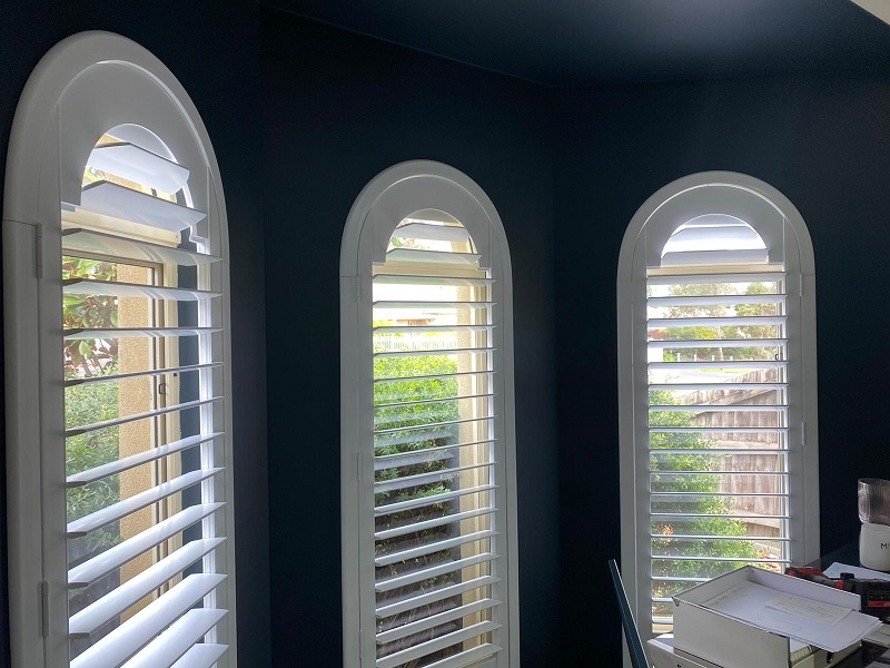 white rounded pvc plantation shutters mounted on windows with black colour walls